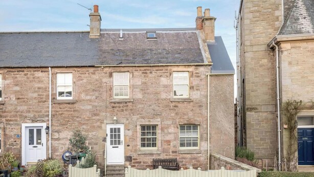 A stone building with a white door, a small window, and a chimney. - Crail Town House (Crail)