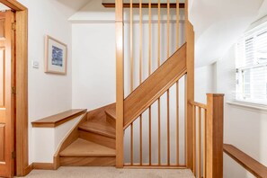 A wooden staircase with a handrail, carpeted floor, and a framed picture on the wall.