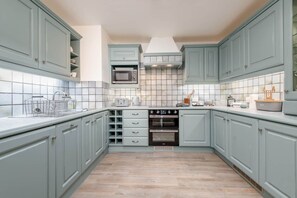 A kitchen with light blue cabinets, a microwave, an oven, and a tiled backsplash.