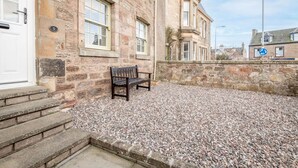 A stone building with a bench, steps, and a pebbled ground. - Crail Town House (Crail)