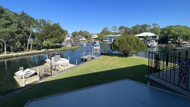 A riverside view with a dock, boats, and houses along the water.