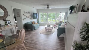 A spacious living area with a dining table, chairs, a sofa, and a TV.