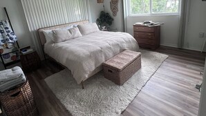 A bedroom with a bed, a ceiling fan, a window, a dresser, and a nightstand.