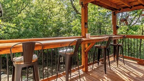 A wooden deck with a wooden table and metal chairs, overlooking a forested area. - Secluded cabin close to Eureka Springs and Table Rock Lake (Eureka Springs)