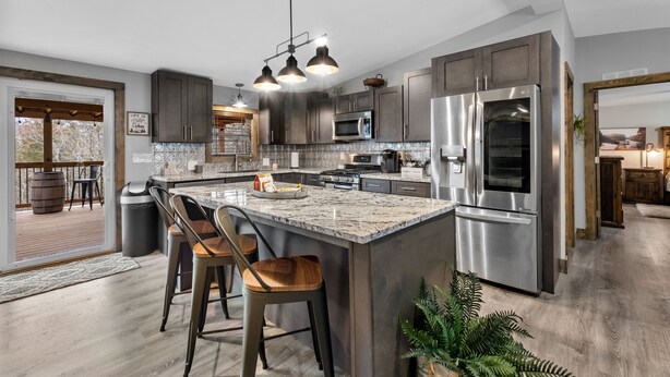 A modern kitchen with dark wood cabinets, stainless steel appliances, and a large island with bar stools. - Secluded cabin close to Eureka Springs and Table Rock Lake (Eureka Springs)