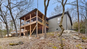 A cabin with a wooden deck and a large window, surrounded by trees and a rocky landscape. - Secluded cabin close to Eureka Springs and Table Rock Lake (Eureka Springs)