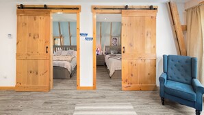 A room with two beds, a blue armchair, and wooden sliding doors. - Perfect location for family vacation or family gathering (Hyde Park)