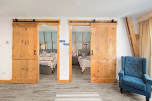 A room with two beds, a blue armchair, and wooden sliding doors.
