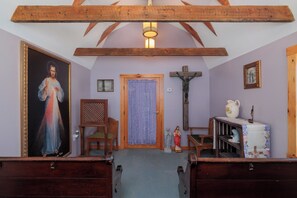 Interior de iglesia con bancas, un crucifijo, una estatua y una pintura.
