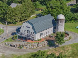 A two-story building with a grey roof and a large silo attached to the right side.