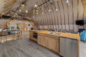 Un'ampia cucina in stile loft con isola centrale, mobili in legno e lavastoviglie in acciaio inossidabile.