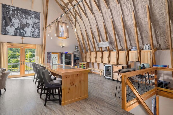 A spacious loft with a high ceiling, a kitchen area, and a dining space with bar stools.
