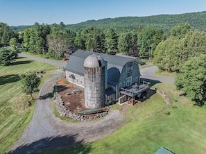 A large barn with a silo, surrounded by a well-maintained lawn and a road.