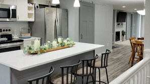Una cocina moderna con una isla central, taburetes de bar e iluminación colgante.