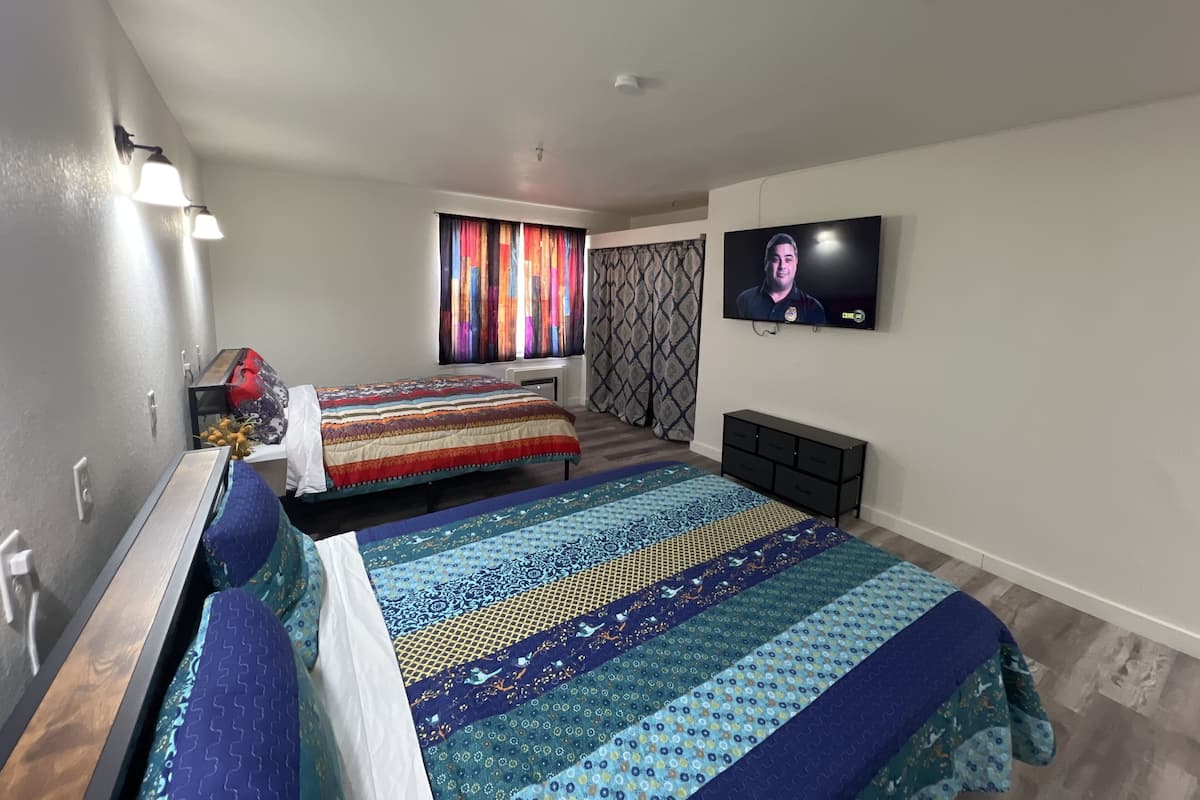 A modern bedroom with two beds, a TV, and a window with colorful curtains.