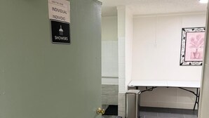 Un couloir avec une porte verte sur laquelle est inscrit : « FERMER À CLÉ – DOUCHES INDIVIDUELLES ».