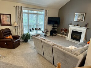 Relax in this inviting living room with a large window, comfortable seating, and a cozy fireplace.