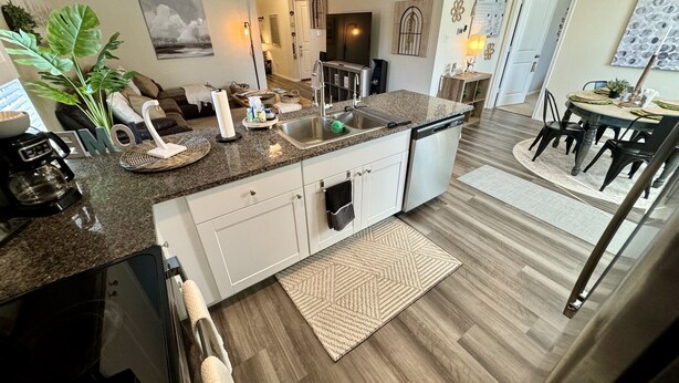 Een moderne keuken met granieten aanrechtbladen, roestvrijstalen apparatuur en een eethoek met een ronde tafel en stoelen.