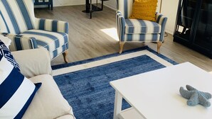 Uma sala de estar com poltronas listradas, uma mesa de centro branca e um tapete azul.