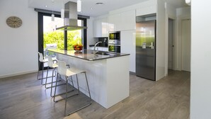 A modern kitchen with a central island, stainless steel appliances, and a large window. - Villa CLANXET (Cambrils)