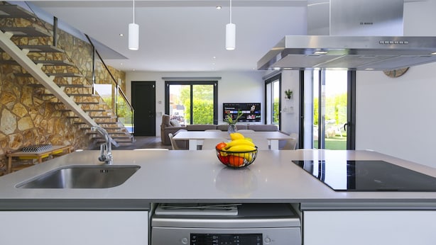 A modern kitchen with a central island, stainless steel appliances, and a stone accent wall. - Villa CLANXET (Cambrils)