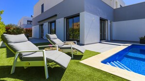 A modern outdoor pool area with lounge chairs and a clear blue pool. - Villa CLANXET (Cambrils)
