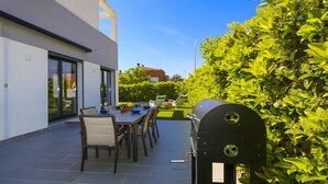 An outdoor patio with a table and chairs, a grill, and a hedge. - Villa CLANXET (Cambrils)