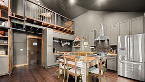 A modern kitchen with a wooden dining table, grey cabinets, and a stainless steel refrigerator. - The Chandler Hotel (Madison)
