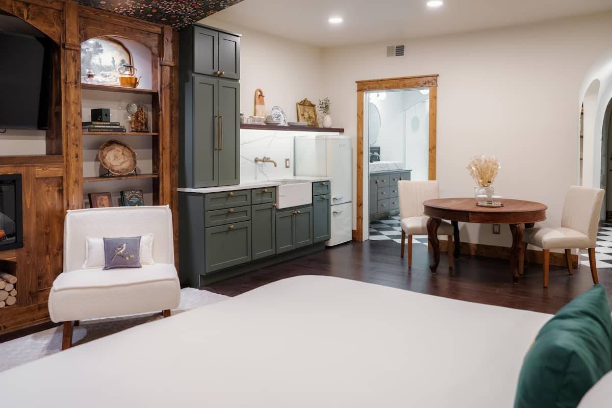 A modern kitchen with a dining area, featuring a white sofa, a round wooden table, and a large mirror.