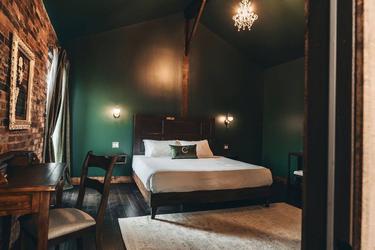 A room with a bed, a wooden table, and a chair.