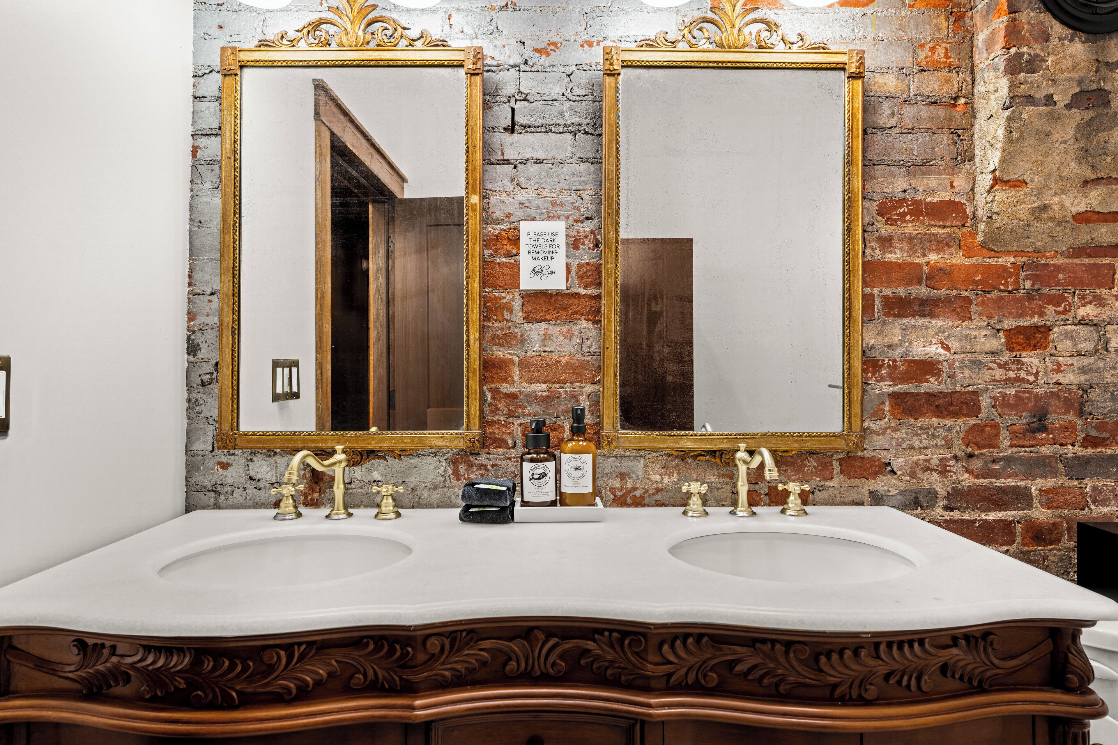 A bathroom with two sinks, a mirror, and a sign on the wall.