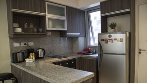 Een moderne keuken met granieten aanrechtbladen, roestvrijstalen apparatuur en houten keukenkastjes.