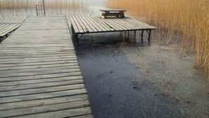 Een houten steiger die zich uitstrekt over een wateroppervlak, met een bankje en een picknicktafel.