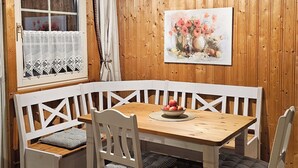 Een houten interieur met een eettafel, bankjes en stoelen.