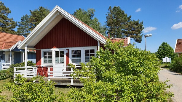 Een rood-wit gebouw met een veranda, omringd door groen.