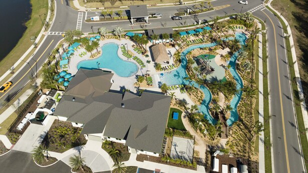 An aerial view of a resort with a large pool area, multiple swimming pools, and a basketball court.