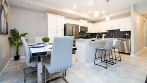 A modern kitchen with white cabinets, stainless steel appliances, and a central island with bar stools.