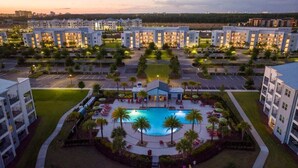 A hotel complex with multiple buildings, a central swimming pool, and surrounding greenery.