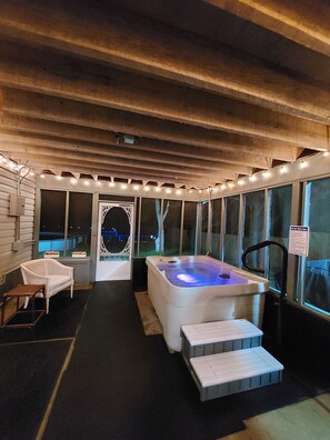 Zona de hidromasaje con techo de madera, una silla blanca y un banco.