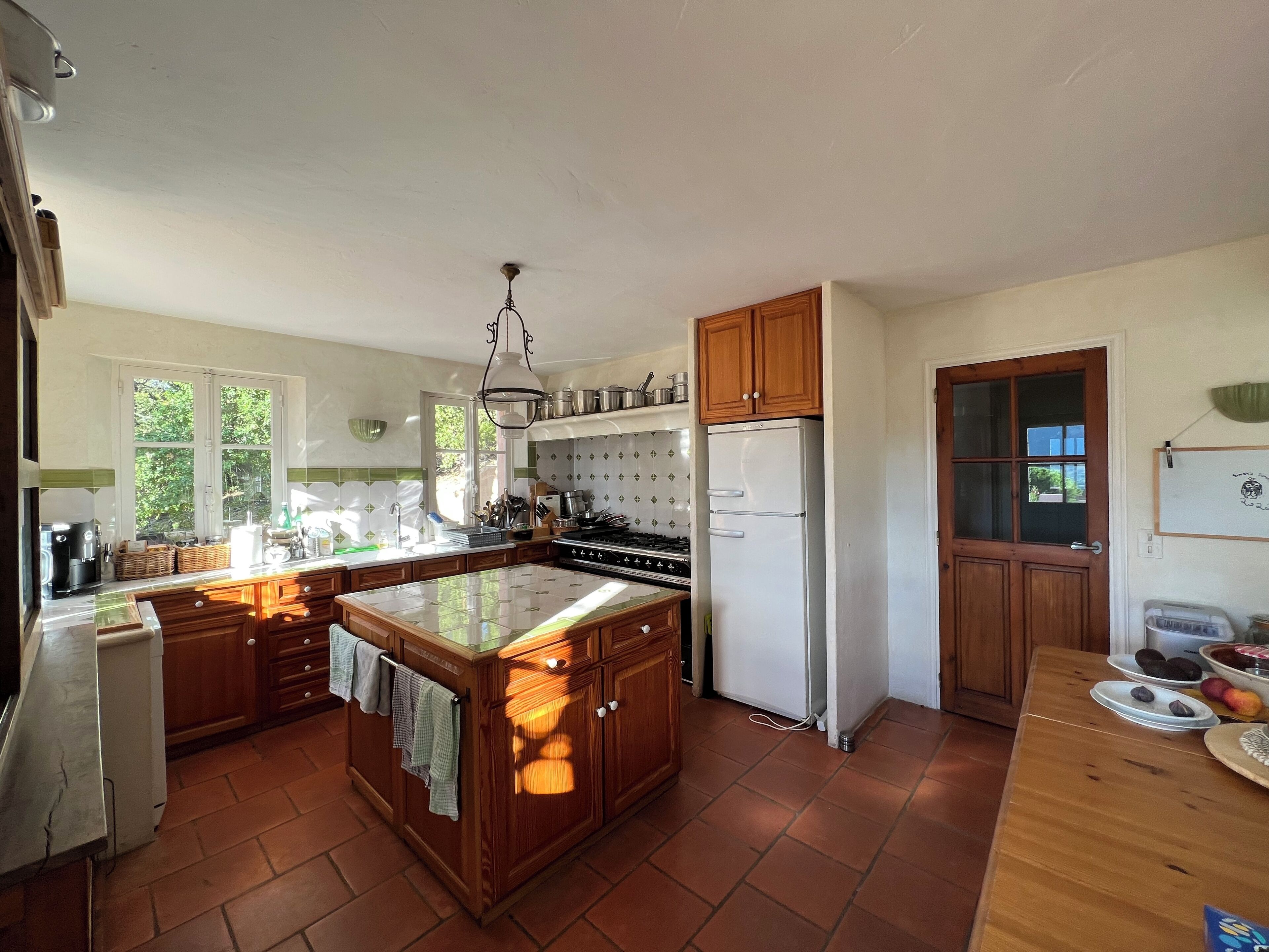 Una cocina amplia con una isla central, armarios de madera, un refrigerador y una estufa.