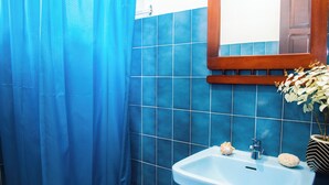 A bathroom with blue tiles, a white sink, a wooden-framed mirror, and a potted plant.