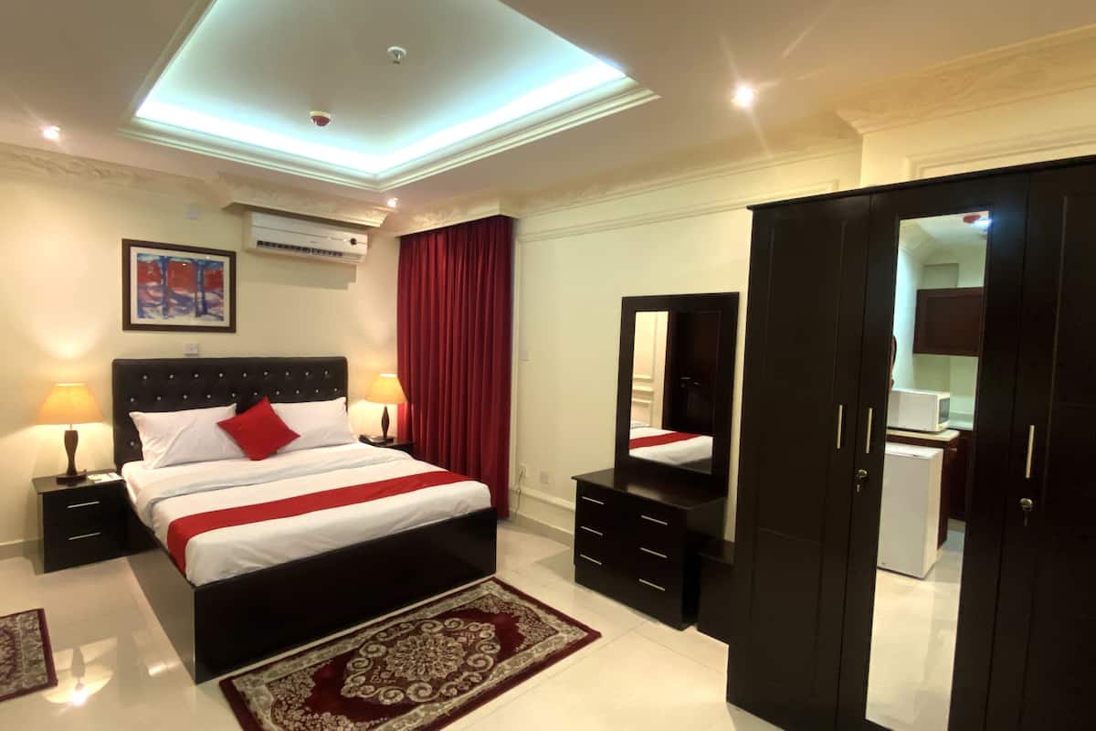 A bedroom with a bed, bedside tables, a mirror, a wardrobe, and a ceiling light fixture.
