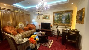 Un salon luxueux comprenant un canapé, un téléviseur, une table à manger, des chaises et un lustre.