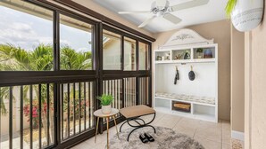 A balcony with a view of palm trees and a white shelf with decorative items. - Luxury Condo in Gated Golf Community close to Beaches (Fort Myers)
