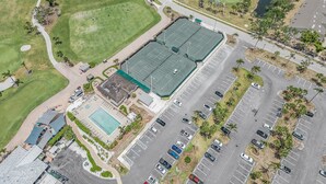 An aerial view of a golf course with a tennis court, parking lot, and a swimming pool. - Luxury Condo in Gated Golf Community close to Beaches (Fort Myers)