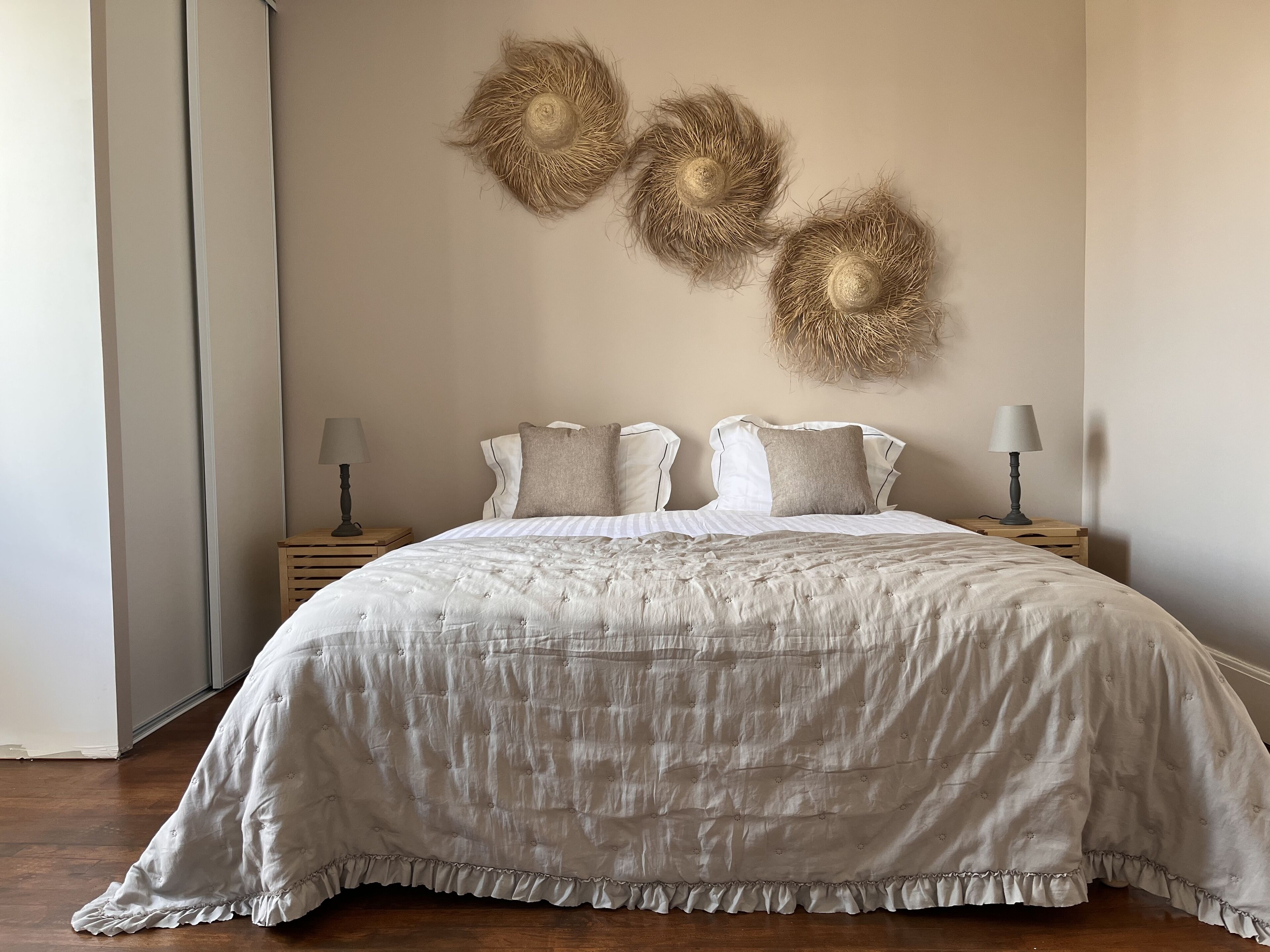 A bedroom with a large bed, two bedside tables, and wall-mounted decorative items.