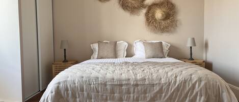 A bedroom with a large bed, two bedside tables, and wall-mounted decorative items.