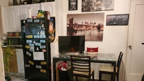 Eine Küche mit Kühlschrank, der mit Magneten und Notizen bedeckt ist, einem Esstisch mit Stühlen und einem Fernseher auf einem Schrank.