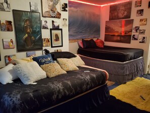 Een slaapkamer met een bed, een sofa en een muur versierd met ingelijste foto’s en een muurschildering.