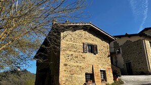 A stone building with a sloped roof, a small porch, and a window.